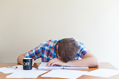 A male is sitting at a desk and sleeping